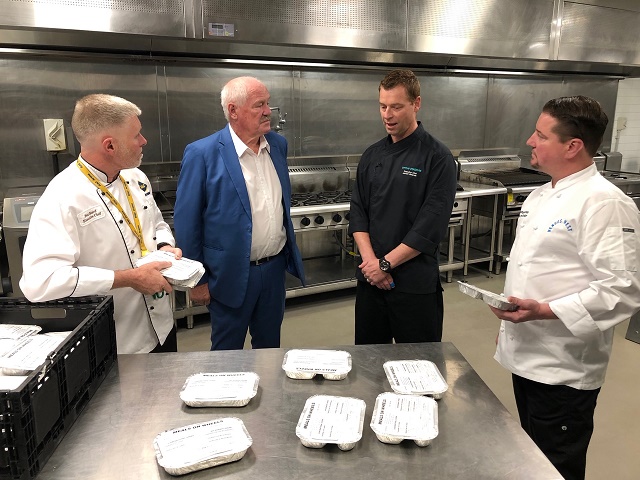 chefs in the kitchen looking at packaged meals