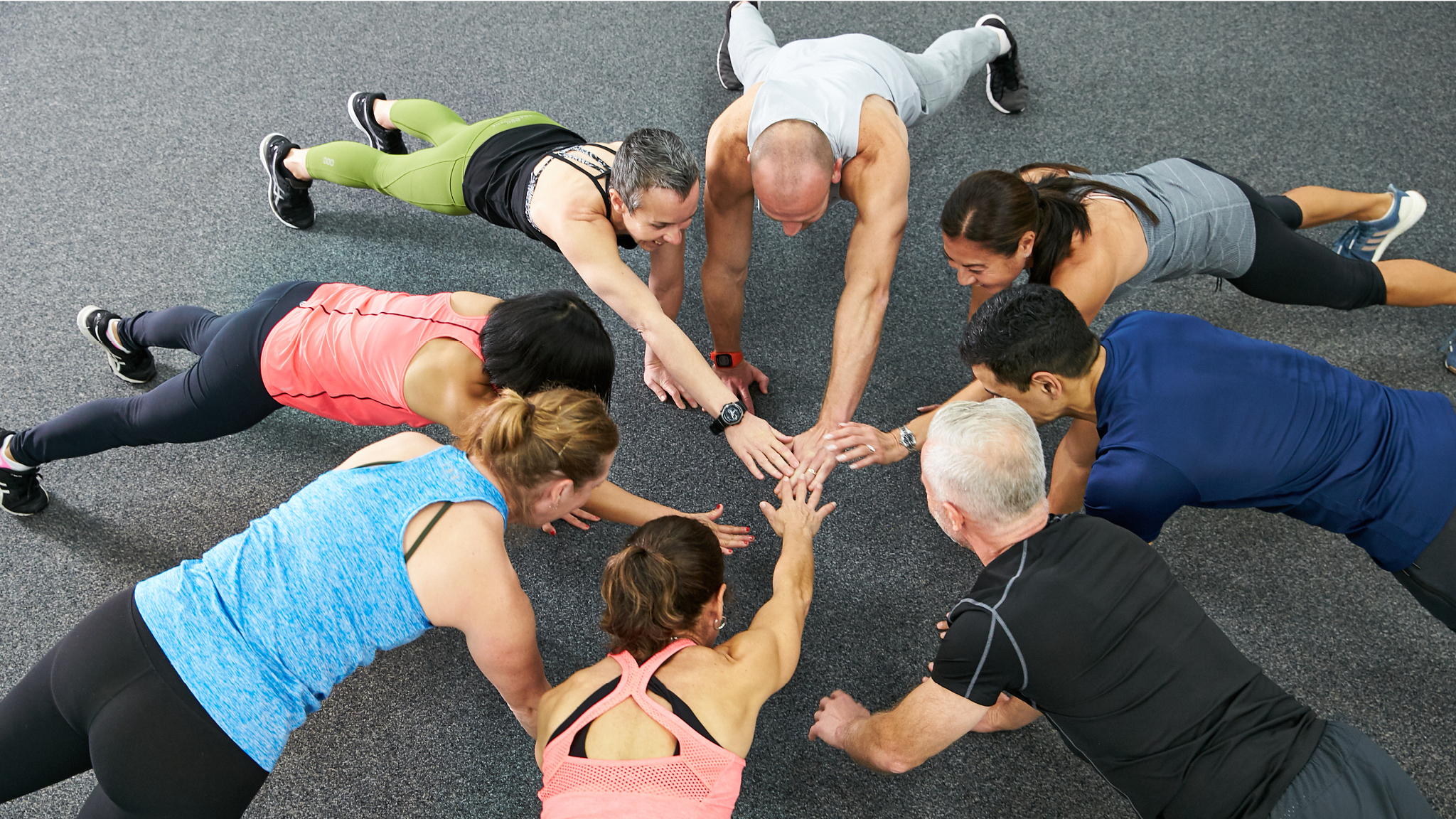 People in push up position in a circle with their hand out