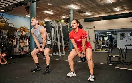 Two gym members lifting kettle bell in Small Group Personal Training class at Perth HPC