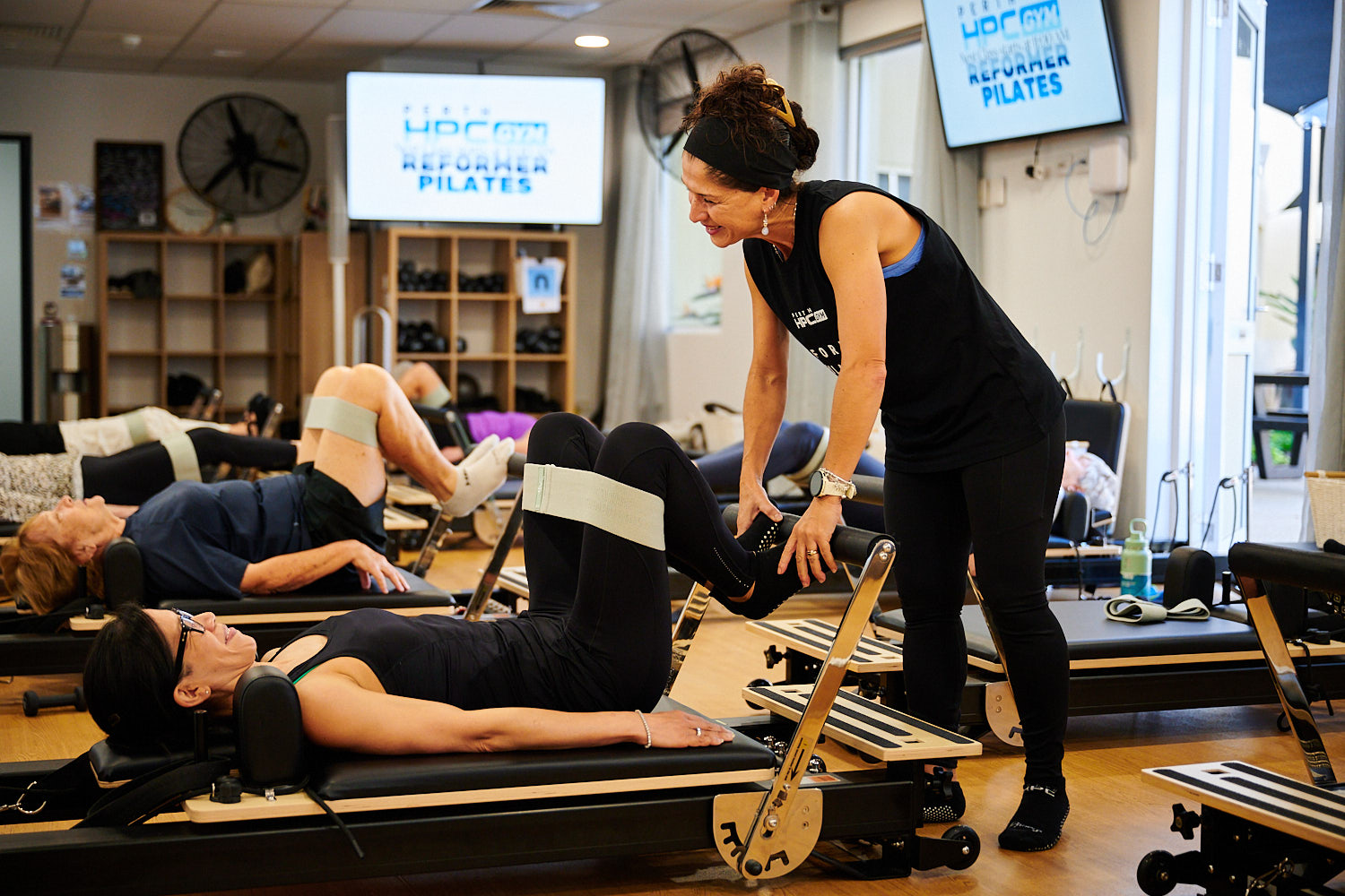 Instructor guiding Reformer Pilates member through an exercise