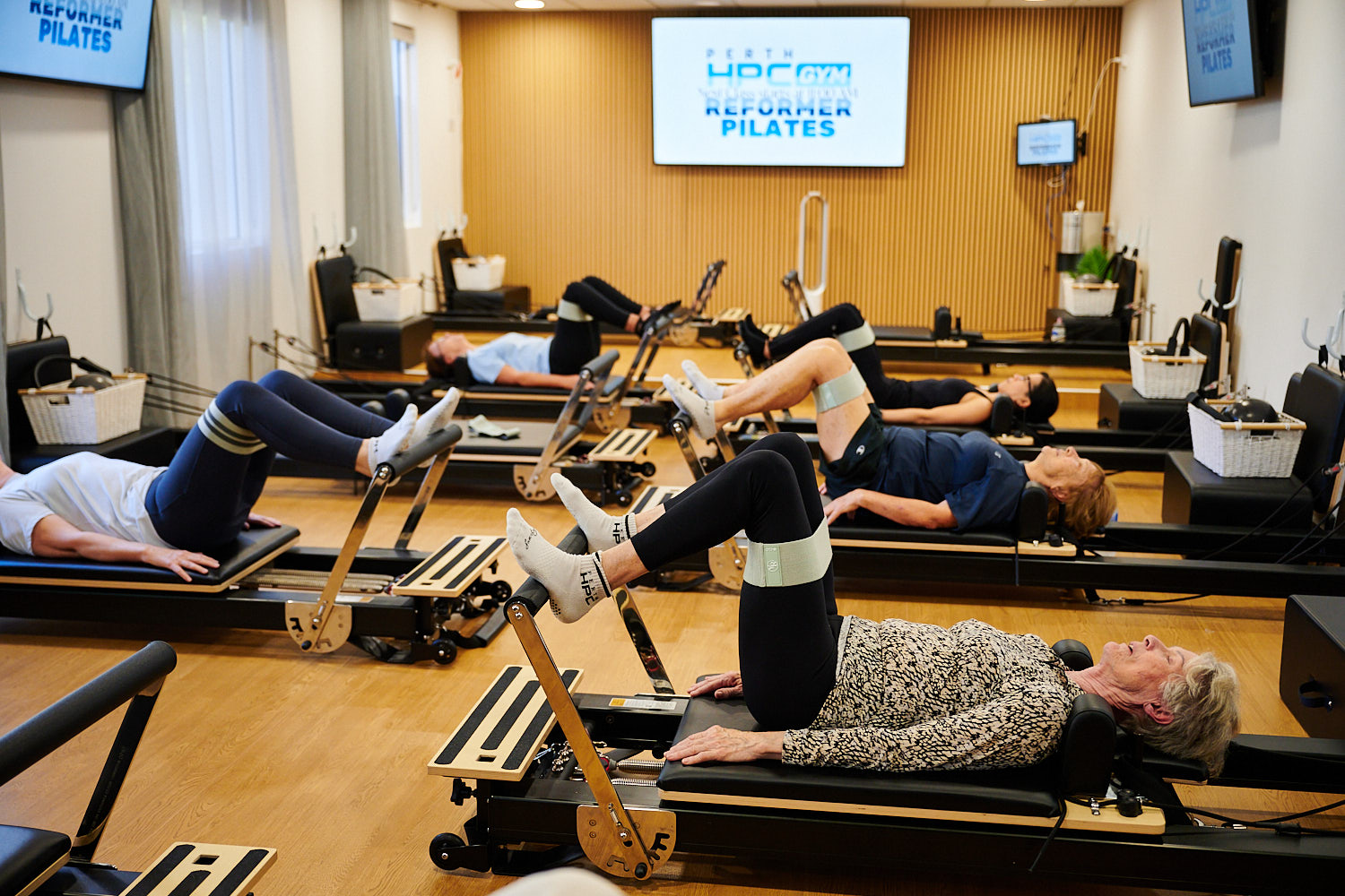 Group of people lying on Reformer Pilates carriages at Perth HPC