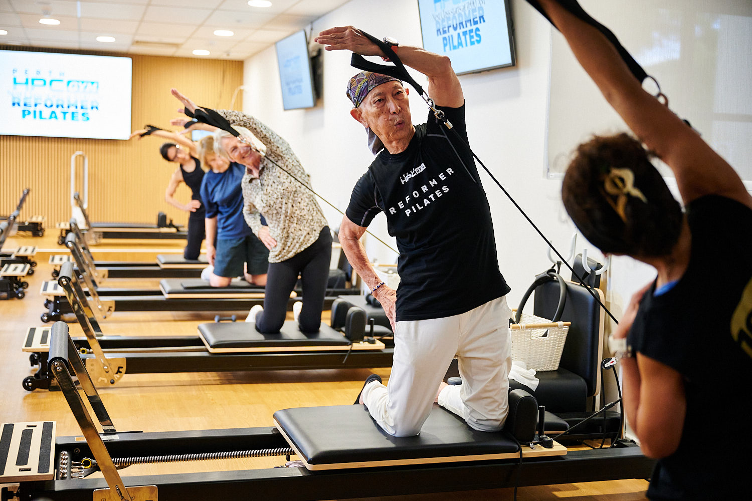 Group of people kneeling on Reformer Pilates carriages using resistance bands at Perth HPC