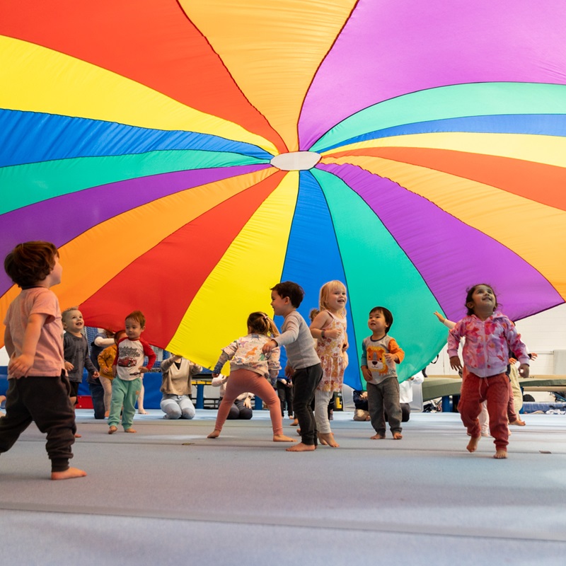 Photo of colourful parachute flying up above children's heads in Perth HPC's Kids Gym class at Mount Claremont, Perth