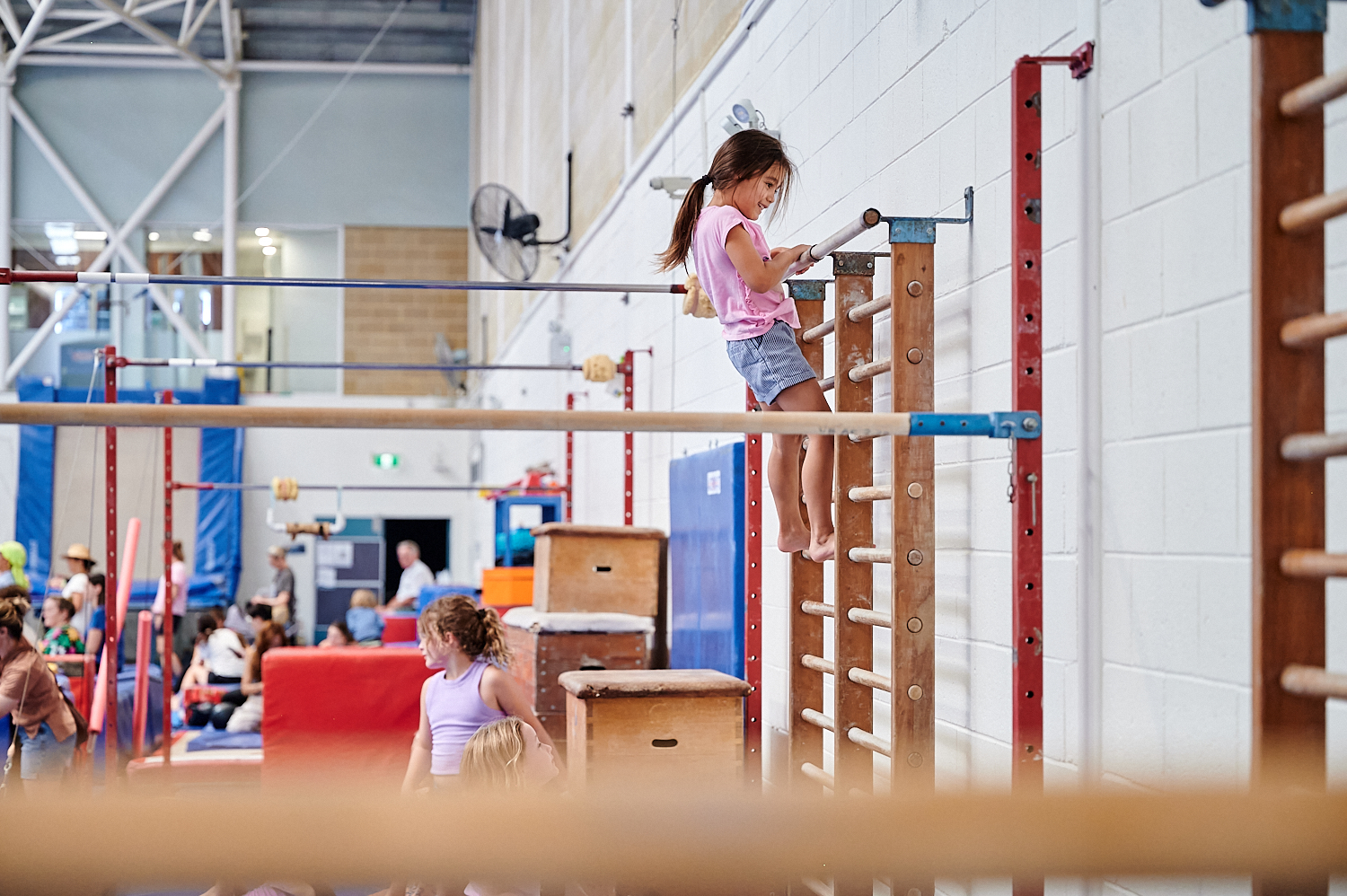 Young girl climbing ladder attached to wall in Kids Gym class at Perth HPC, Mount Claremont, Perth