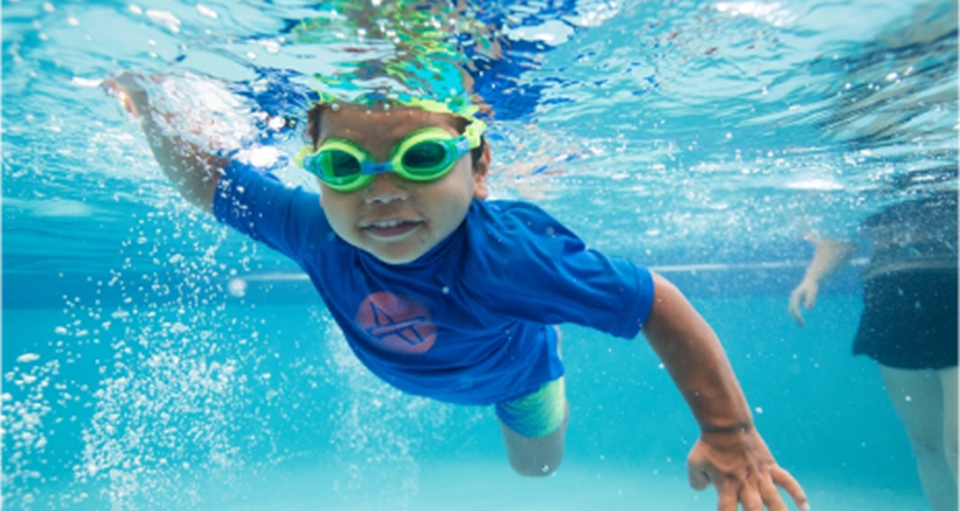 Underwater view of happy young boy swimming freestyle