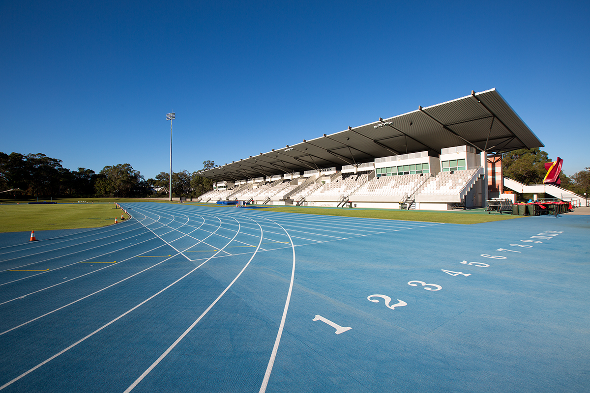 A photo of the start of the sprint track at the WA Athletics Stadium with grandstand seating in the background